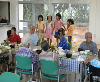 ▲生活支援ハウスを利用する高齢者と一緒に「いただきます」をする園児たち。